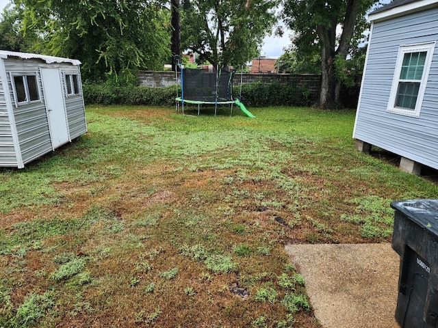 view of yard with a trampoline and a storage unit