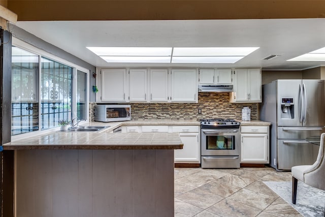 kitchen with white cabinetry, appliances with stainless steel finishes, backsplash, sink, and kitchen peninsula