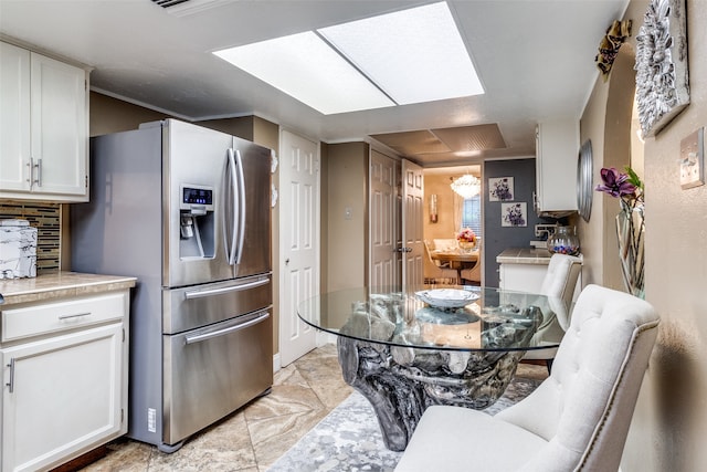 kitchen featuring stainless steel fridge with ice dispenser and white cabinetry