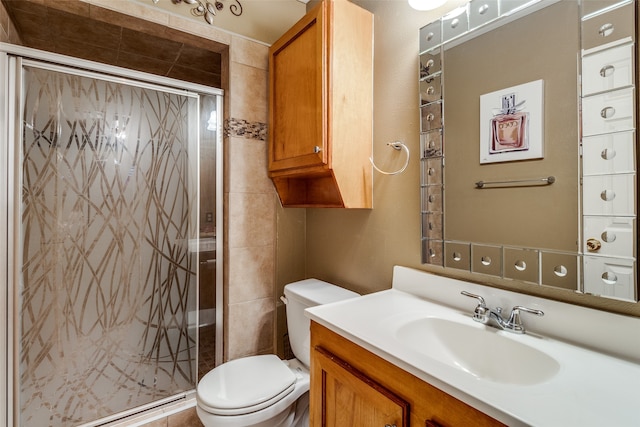 bathroom featuring toilet, vanity, and a shower with shower door