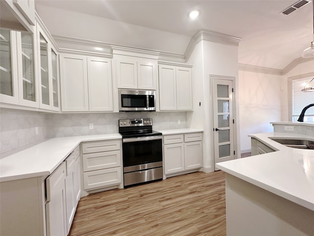 kitchen with stainless steel appliances, decorative backsplash, sink, white cabinetry, and light wood-type flooring