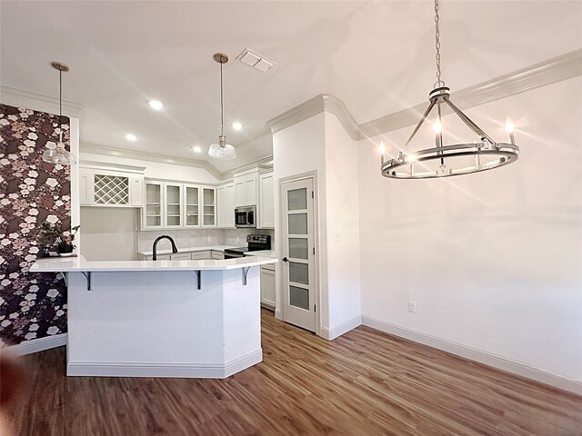 kitchen featuring white cabinets, a kitchen breakfast bar, hanging light fixtures, and dark wood-type flooring