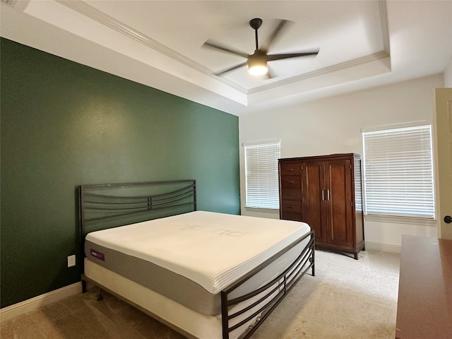 carpeted bedroom with ceiling fan and a tray ceiling