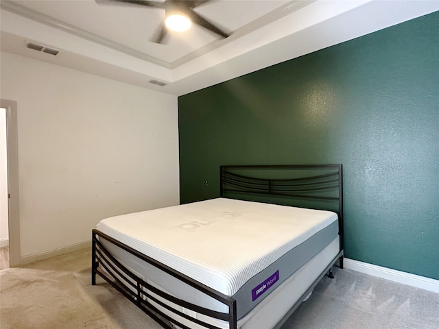 bedroom with light colored carpet, ceiling fan, and a raised ceiling