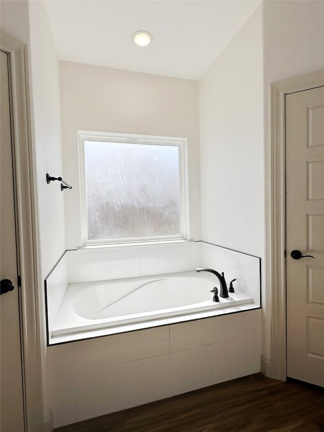 bathroom featuring wood-type flooring and tiled tub