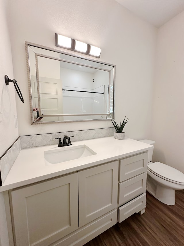 bathroom with vanity, hardwood / wood-style flooring, toilet, and a shower