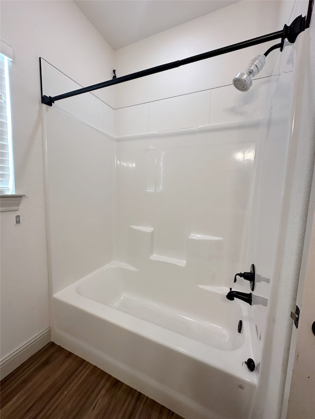 bathroom featuring a healthy amount of sunlight, hardwood / wood-style flooring, and shower / washtub combination