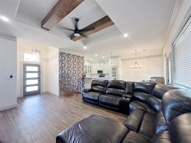 living room featuring light wood-type flooring, ceiling fan with notable chandelier, ornamental molding, and beam ceiling