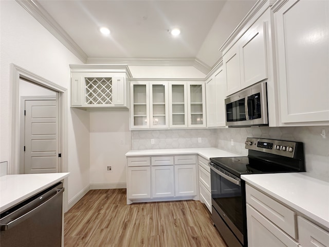 kitchen featuring crown molding, light wood-type flooring, white cabinetry, appliances with stainless steel finishes, and backsplash