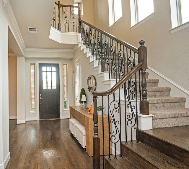 entrance foyer featuring a towering ceiling, dark hardwood / wood-style floors, and crown molding