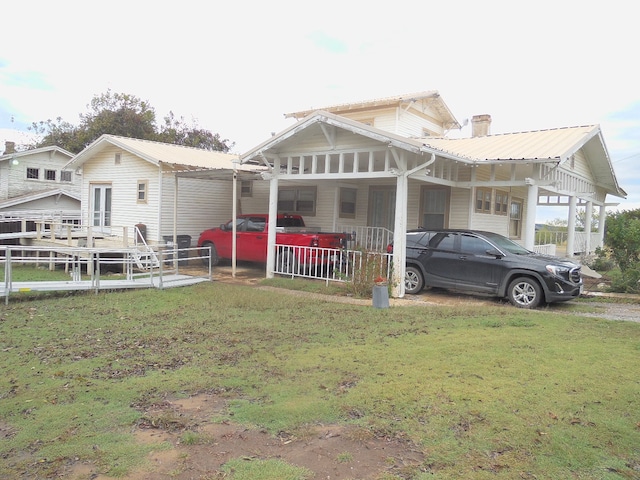 rear view of house with a porch, a lawn, and a carport