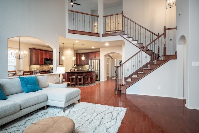 living room featuring dark wood-type flooring, a high ceiling, and a notable chandelier