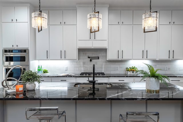 kitchen featuring hanging light fixtures, a kitchen island with sink, and dark stone counters