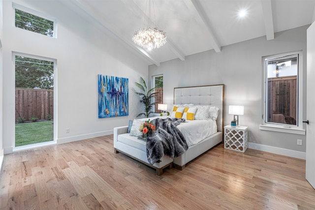 bedroom with lofted ceiling with beams, light wood-type flooring, and an inviting chandelier