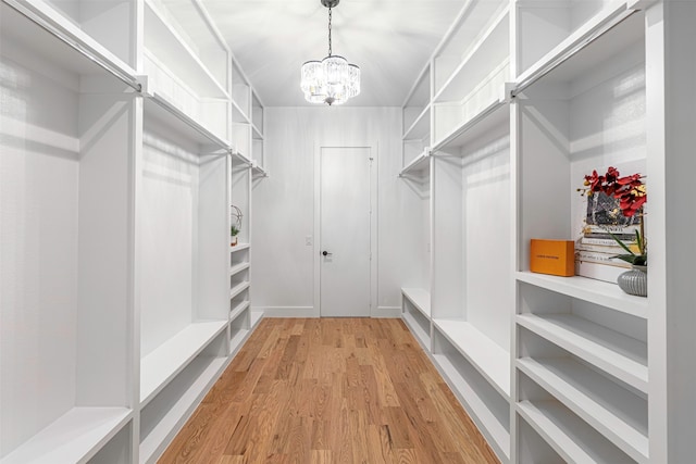 walk in closet featuring light hardwood / wood-style floors and a chandelier