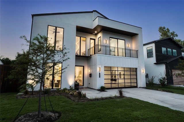 modern home featuring a garage, a balcony, and a yard