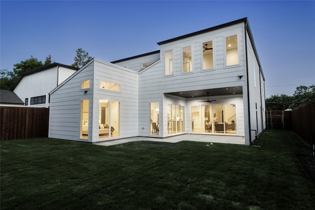 back house at dusk with a patio area, ceiling fan, and a yard