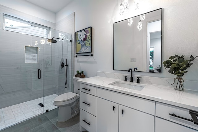 bathroom with vanity, a shower with shower door, and toilet