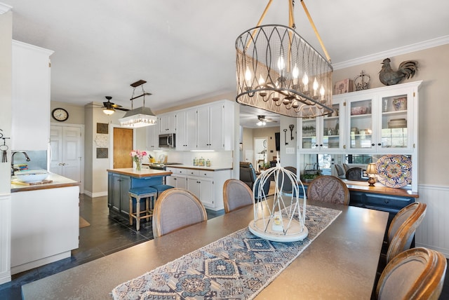 dining room featuring sink, ceiling fan with notable chandelier, and crown molding