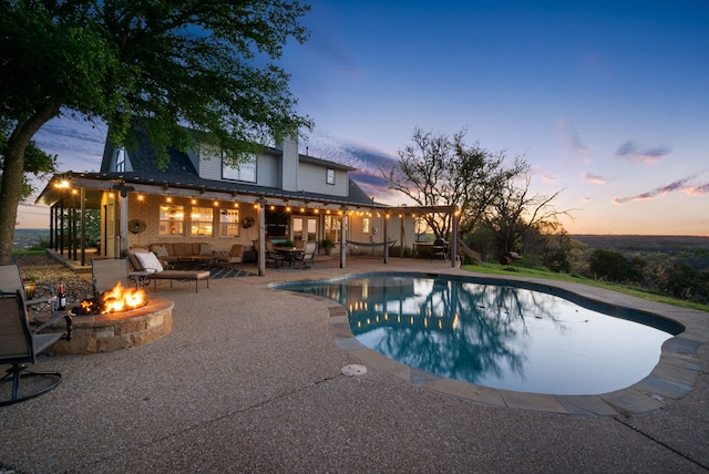 pool at dusk featuring a fire pit and a patio