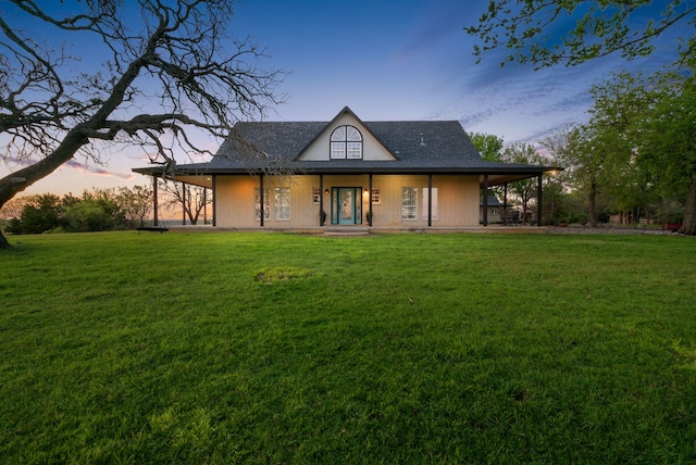 back house at dusk with a porch and a yard