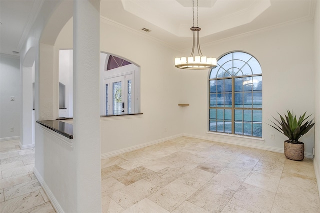 unfurnished room featuring a tray ceiling, ornamental molding, and a chandelier