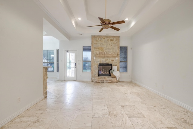 unfurnished living room featuring ceiling fan, a stone fireplace, and a tray ceiling