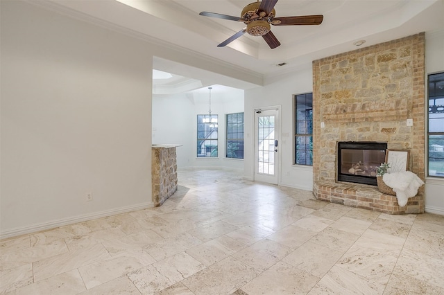 unfurnished living room with ceiling fan with notable chandelier, a tray ceiling, crown molding, and a fireplace