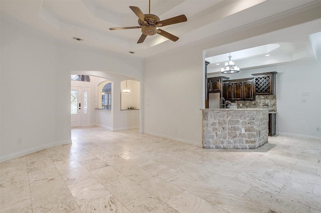 unfurnished living room with crown molding, ceiling fan with notable chandelier, and a tray ceiling