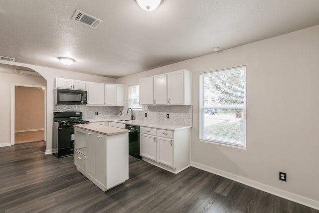 kitchen with white cabinets, black appliances, a healthy amount of sunlight, and a kitchen island