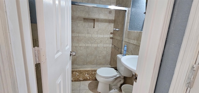 bathroom with tile patterned flooring, toilet, and a tile shower