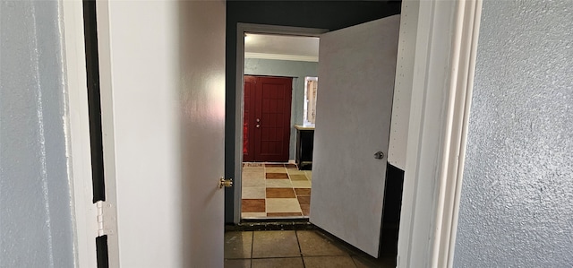 hall with dark tile patterned floors and ornamental molding