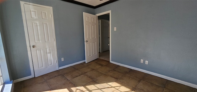 unfurnished bedroom with dark tile patterned floors and ornamental molding