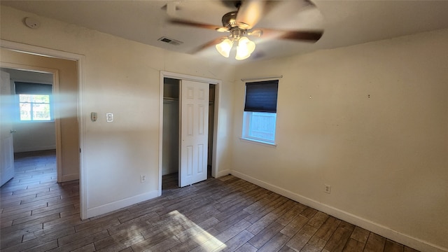 unfurnished bedroom with dark wood-type flooring, ceiling fan, and a closet