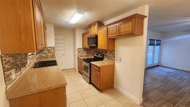 kitchen featuring decorative backsplash, light stone countertops, stainless steel appliances, sink, and light tile patterned flooring