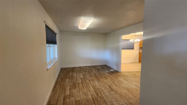 empty room featuring a chandelier and light hardwood / wood-style floors