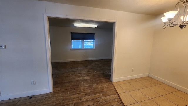 empty room with a notable chandelier and wood-type flooring