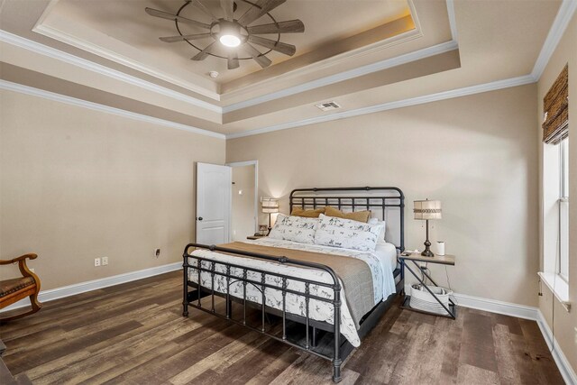 bedroom with crown molding, ensuite bath, hardwood / wood-style floors, a tray ceiling, and ceiling fan