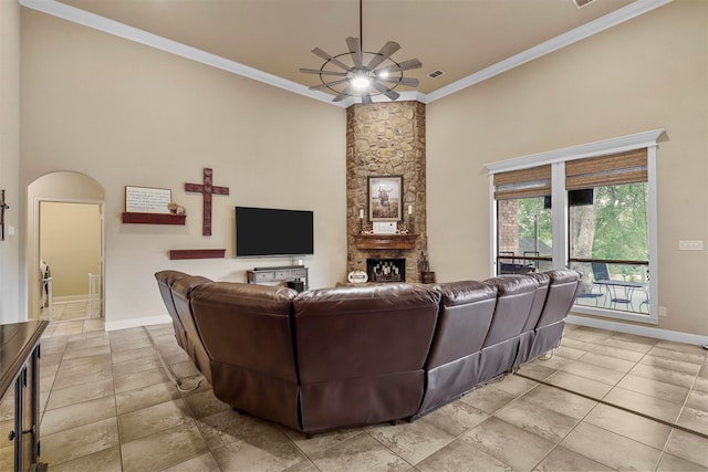 living room featuring a fireplace, a towering ceiling, ceiling fan, and crown molding