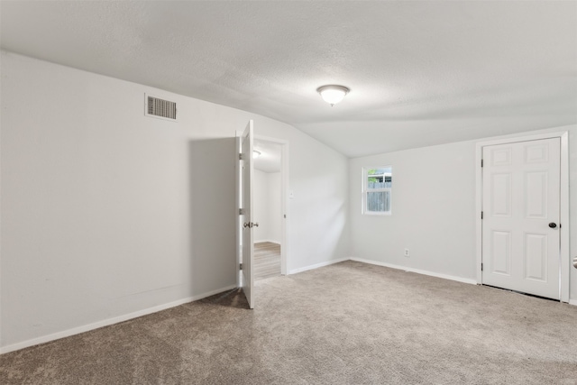 bonus room with carpet floors, lofted ceiling, and a textured ceiling