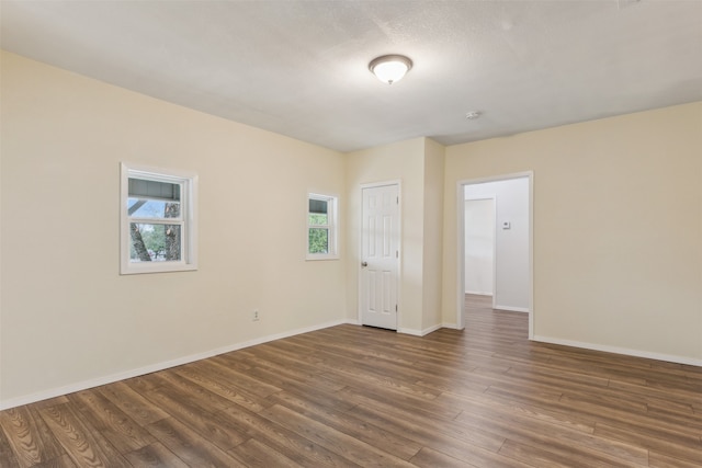 spare room with a wealth of natural light and dark hardwood / wood-style flooring