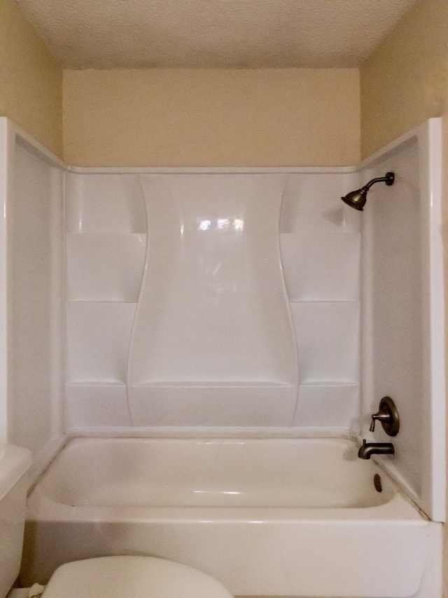 bathroom featuring a textured ceiling, toilet, and bathtub / shower combination