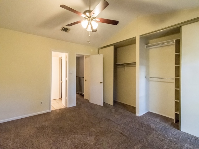 unfurnished bedroom with two closets, vaulted ceiling, ceiling fan, and dark carpet