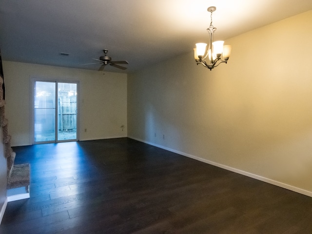 empty room with dark hardwood / wood-style floors and ceiling fan with notable chandelier