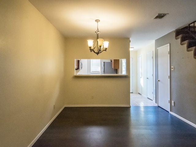 unfurnished room with a chandelier and hardwood / wood-style floors