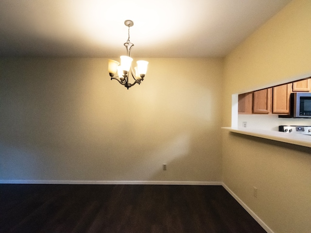 unfurnished dining area with dark hardwood / wood-style floors and a chandelier