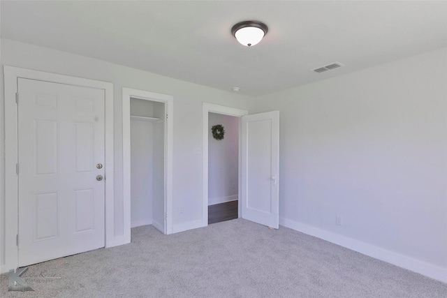 unfurnished bedroom with light carpet and a closet