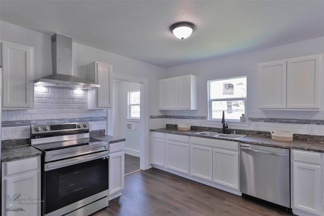 kitchen featuring white cabinetry, a wealth of natural light, stainless steel appliances, and wall chimney range hood