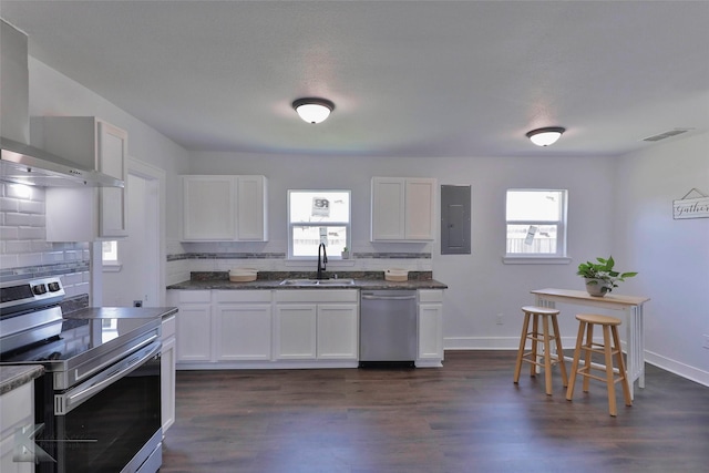 kitchen with wall chimney exhaust hood, sink, white cabinetry, appliances with stainless steel finishes, and electric panel