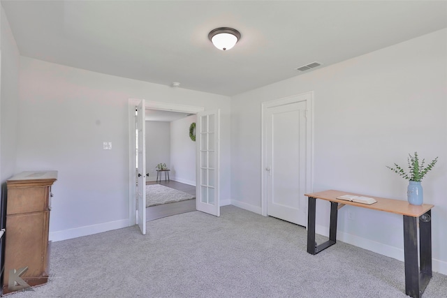 interior space featuring light colored carpet, a closet, and french doors